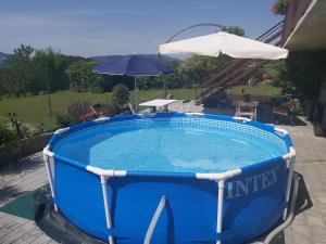 a large blue pool with an umbrella and a table and chairs at Haus Fernblick in Birkfeld