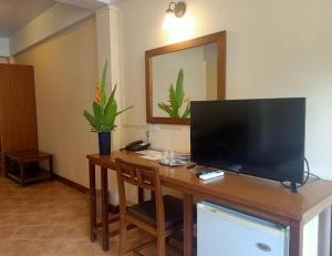 einen Schreibtisch mit einem TV darüber in der Unterkunft Sun Hotel in Phetchaburi