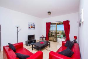 a living room with a red couch and a table at Iliada Villa 4 in Peyia