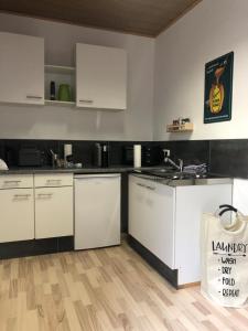 a kitchen with white cabinets and a wooden floor at Apartment 1 in Korschenbroich