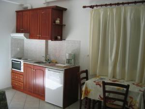 cocina con armarios de madera, fregadero y mesa en Nikas Villa Orange Apartments , en Parga