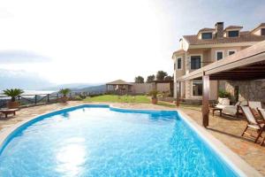 a large blue swimming pool in front of a house at Villa Hestia in Agios Nikolaos