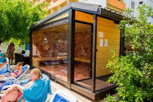 a woman is sitting in chairs in front of a tiny house at Hotel Majestic Mamaia Half Board & All Inclusive in Mamaia