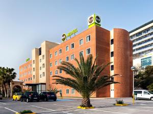 un bâtiment avec un palmier dans un parking dans l'établissement B&B HOTEL Alicante, à Alicante