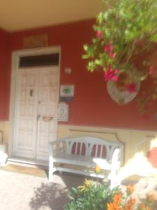 un banco blanco sentado frente a una puerta en B&B Le Stanze del Moro, en Pállare