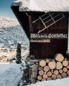 a building with a pile of logs in the snow at Hotel Mas de la Coutettaz, The Farmhouse in Morzine