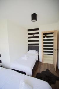 1 Schlafzimmer mit 2 Betten und einer Tür zu einem anderen Zimmer in der Unterkunft MOKAA Apartment in Mostar