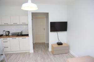 a kitchen with white cabinets and a flat screen tv on a wall at Apartament Sopot in Sopot
