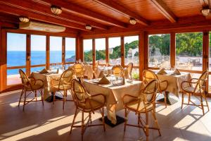 a restaurant with tables and chairs and a view of the ocean at Hotel Baia Imperiale in Campo nell'Elba