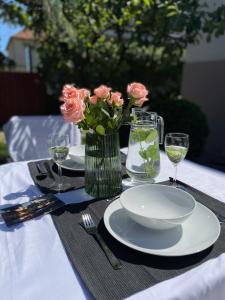 a table with plates and a vase of pink roses at Apartament2 Tri-City Oliwa Ogród, prywatne wejście in Gdańsk