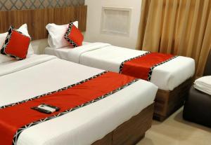 - deux lits dans une chambre d'hôtel rouge et blanche dans l'établissement EMPIRE INN HOTEL, à Chennai