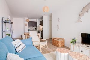 a living room with a blue couch and a kitchen at Ressourcez vous dans ce bel appartement a Lacanau in Lacanau