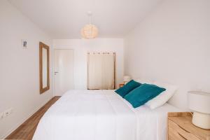 a white bedroom with a large white bed with a blue pillow at Ressourcez vous dans ce bel appartement a Lacanau in Lacanau