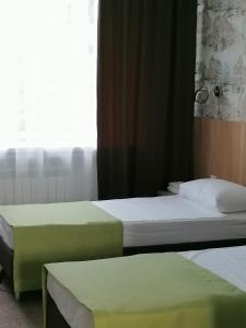 two twin beds in a room with a window at Gostinitsa on Martemyanova in Kemerovo