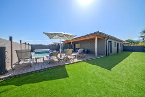 une terrasse avec une table, des chaises et un parasol dans l'établissement Résidence Pierre & Vacances Premium Vesna Rossa, à Porto-Vecchio