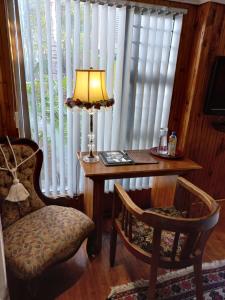 una mesa con una lámpara y una silla junto a una ventana en Belurana River Manor, en Upington