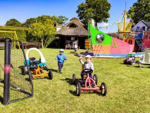 two children riding on toy cars in a park at Pokoje gościnne Jolka in Łeba