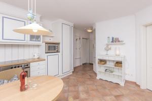 a kitchen with white cabinets and a wooden table at Villa Strandperle Nr. 17 in Binz