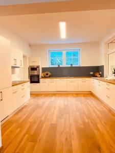 uma grande cozinha com armários brancos e piso em madeira em Alte Mühle em Holzminden