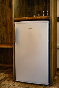 a white refrigerator in a kitchen with a wooden wall at Place near beach in Pērkone