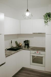 a white kitchen with a sink and a stove at SunsetView Apartment in Oradea