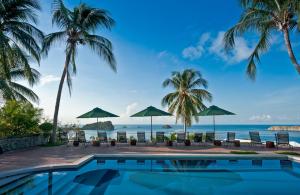 a swimming pool with palm trees and the ocean at Hotel Costa Verde in Manuel Antonio