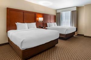ブルームフィールドにあるComfort Suites Broomfield-Boulder-Interlockenの白いシーツが敷かれたホテルの部屋にベッドが2つある