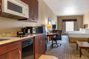 a hotel room with a kitchen and a bed at Quality Inn & Suites in Rimbey