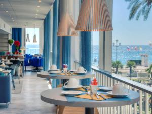 a restaurant with tables and a view of the ocean at Mercure Nice Promenade Des Anglais in Nice