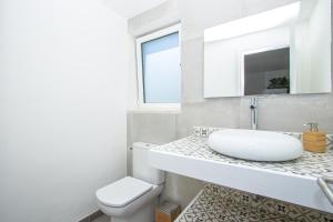 a white bathroom with a sink and a toilet at Apartment Jedy Balear By homevillas360 in Son Serra de Marina