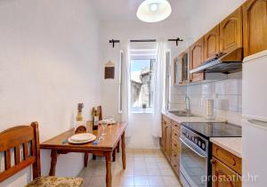 a kitchen with a wooden table and a dining table at Apartment Seka Oldtown in Senj