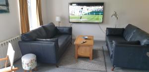 a living room with two couches and a tv at One The Cairns in Connel