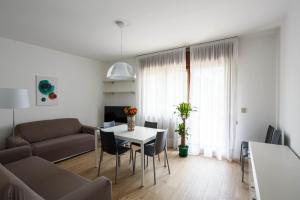ein Wohnzimmer mit einem Sofa und einem Tisch mit Stühlen in der Unterkunft Appartamento Calmo 1SX in Lido di Venezia