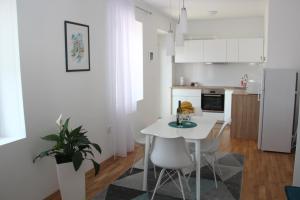 a white kitchen with a white table and chairs at Apartment Lana in Tivat