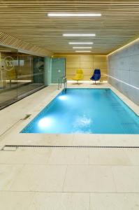 a swimming pool in a building with two blue chairs at Kamieniec 27 Bed & Breakfast in Zakopane