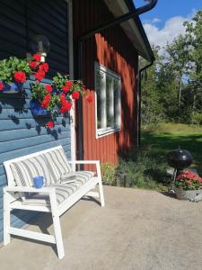 a white bench sitting outside of a house with flowers at Bolmen Bed - Vandrarhem in Ljungby