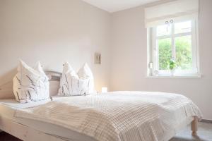 a white bedroom with a white bed with white pillows at Alva in Sondershausen