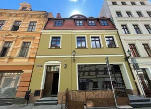 トルンにあるApartamenty Małe Garbaryの赤屋根の黄色い建物