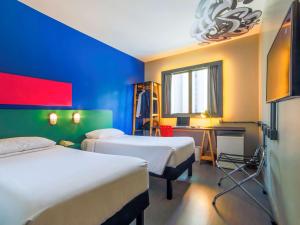 a room with two beds and a desk with a window at ibis Styles SP Faria Lima in Sao Paulo