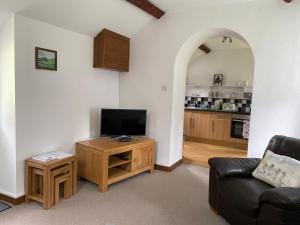 a living room with a couch and a tv and a table at Cwt Mochyn in Corwen