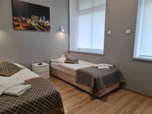 two beds in a room with two windows at Apartament dwupoziomowy Kłodzko - Centrum in Kłodzko