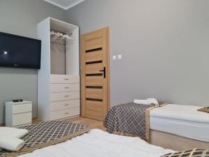 a bedroom with two beds and a tv and a closet at Apartament dwupoziomowy Kłodzko - Centrum in Kłodzko +1 photo