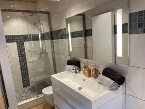 a white bathroom with a sink and a shower at La Petite Maison au bord de l'eau in Hastière-par-delà +6 photos