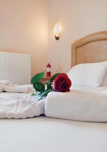 a white bed with a red rose on it at Epidavria Hotel in Tolo