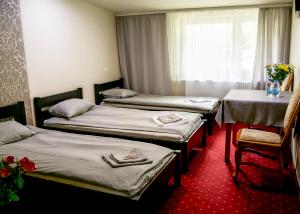 a room with three beds and a table and a window at Kamionki in Sosnowiec