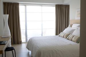 a bedroom with a bed and a large window at Sandy Beach Hotel & Spa - ex Sentido in Larnaca