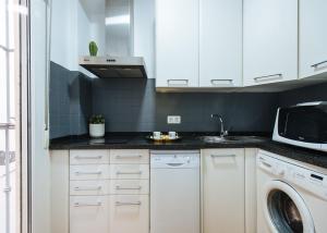 cocina con armarios blancos y lavadora en Magno Apartments Feijóo, en Sevilla