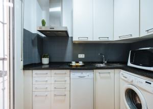 een keuken met witte kasten en een wasmachine bij Feijóo Suite Apartment in Sevilla
