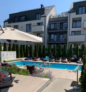 a swimming pool with people laying in chairs next to a building at Old Mill Apartamentai - Palanga in Palanga