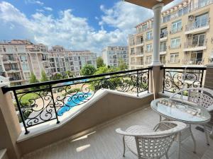 a balcony with a table and chairs and a view of buildings at Izida Palace Apartments in Sunny Beach